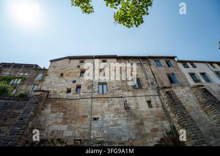 Low-angle shot of historic stone retaining walls and medieval Renaissance residential facades against a bright blue sky in the Ville Haute district of Stock Photo