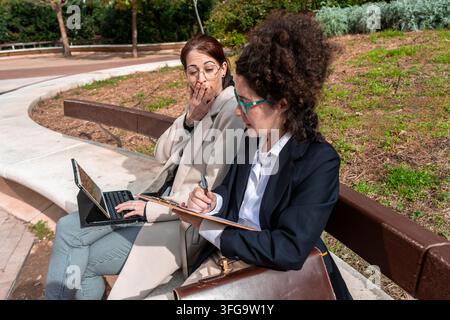 Women collaborating on business project in park Stock Photo
