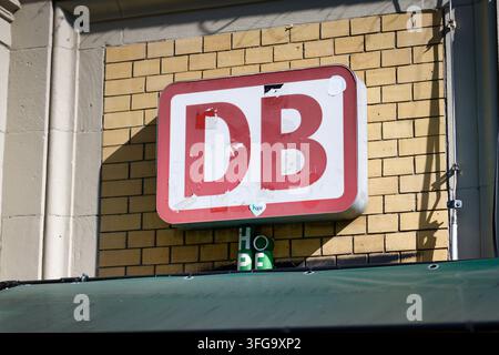 Cologne, Germany September 10 2026: Slightly weathered red and white Deutsche Bahn DB logo sign mounted on a light yellow brick wall at a train statio Stock Photo