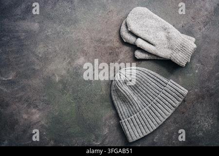 Gray knitted hat and mittens on a dark rustic background. Winter and autumn clothes. Top view, flat lay, copy space Stock Photo