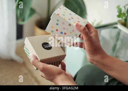 Two hands holding gift boxes in a bright room with plants Stock Photo