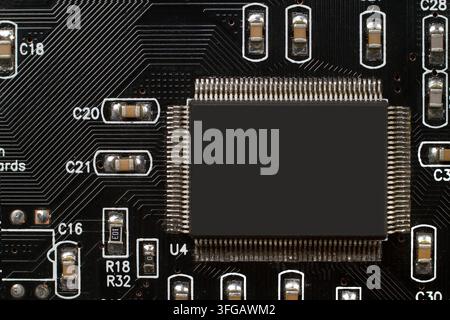 Microchip on a black printed circuit board. Electronic component with integrated circuits Stock Photo