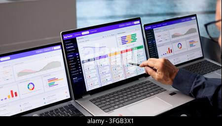 Software Developer Reviews Bug Tracking Dashboard On Laptop During Sprint. Stock Photo