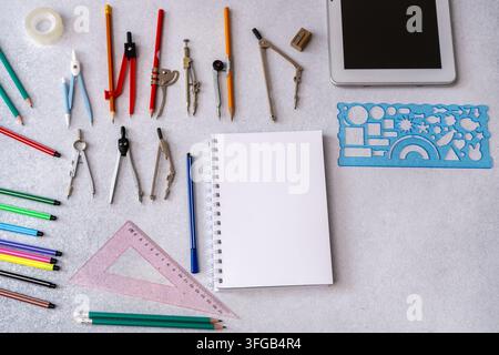 Geometry tools, pencils, and empty notebook on a desk. Drafting and engineering stationery flat lay for education. Home work for studying at school. Stock Photo