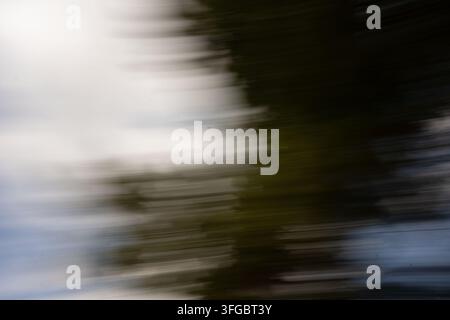 abstract motion-blurred landscape viewed in transit, with layered horizontal streaks of charcoal, blue-gray, olive, and white creating a quiet, cinema Stock Photo
