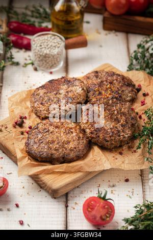 Fried beef cutlets on wooden board with herbs Stock Photo