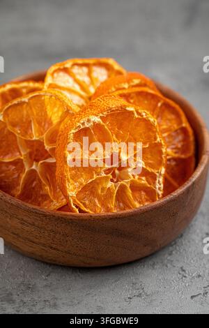 Dried orange slices in wooden bowl on stone Stock Photo