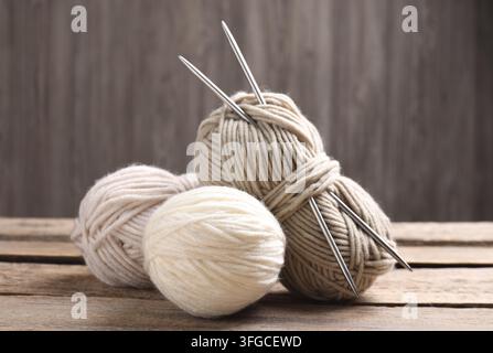Knitting yarns and needles on wooden table, closeup Stock Photo
