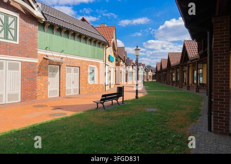 Scenic view of an empty pedestrian street in a European style suburban town with classic brick facades, tiled roofs, street lamps, and a green lawn Stock Photo