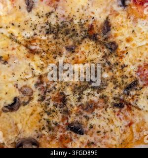 A round cheese pizza with melted cheese and mushrooms is placed on a wooden table. Dried herbs are sprinkled on top, enhancing the flavor. The pizza i Stock Photo