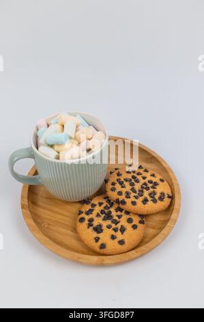 Pastel Marshmallows in Cup with Chocolate Chip Cookies on Wooden Plate Stock Photo