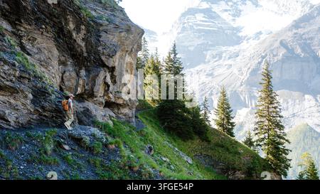 Discover the stunning landscapes of Oeschinensee in Kandersteg, Switzerland, as a hiker explores the scenic trails surrounded by majestic mountains an Stock Photo