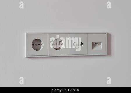 Close up of white recessed wall plate featuring two round socket openings and small switch panel, clean minimalist design suited for home office, livi Stock Photo