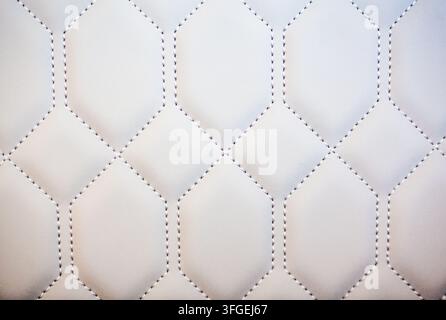 Close-up macro view of white quilted faux leather upholstery with a geometric stitched hexagonal and diamond pattern, Portugal Stock Photo