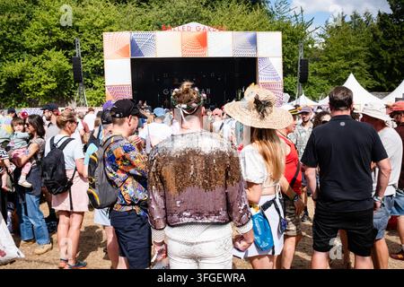 FESTIVAL CROWD AT THE WALLED GARDEN STAGE, REPORTAGE, GREEN MAN FESTIVAL 2026, BRECON, WALES, UK, 2026: Seen from behind, a festival-goer wearing a striking silver sequin jacket and a flower chaplet stands in the crowd watching a performance on the Walled Garden stage. Photo: Rob Watkins. INFO: The Green Man Festival is held in the Brecon Beacons in August. It celebrates alternative music, arts, literature, science and family-friendly culture in a beautiful mountain setting. The 2026 event took place during rainstorms at the end of a long heatwave and drought. Stock Photo