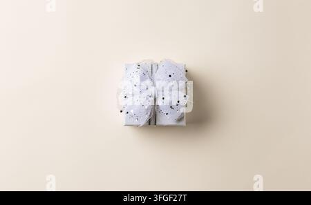 Small white Christmas gift box centered on beige background with wide copy space for New Year sale, greeting card or festive design Stock Photo