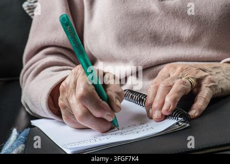 Elderly persons hands in close-up showing wrinkling & visible joint changes where joint enlargement may affect writing. Stock Photo