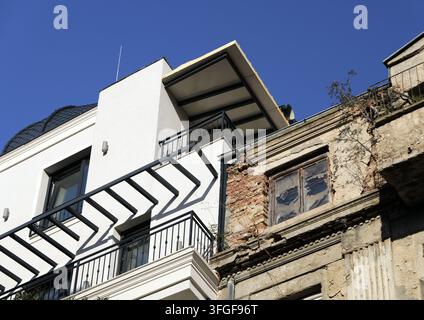 Renovated white facade beside a crumbling brick building, highlighting gentrification and urban contrast in a sunny city block. Bulgaria, varna, 11 se Stock Photo