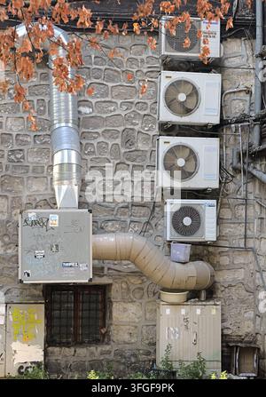 Multiple air conditioning units and large industrial ventilation ducts creating a complex system on an old stone wall facade. Bulgaria, varna, 11 sept Stock Photo