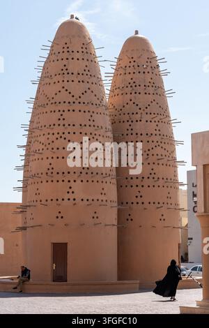 Katara, Doha, Qatar - February 11, 2026: A vertical exterior daytime view of the back view of a woman wearing a traditional abaya walking away. Stock Photo
