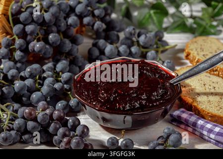 Grapes and marmalade next to slices of bread on wooden table Stock Photo