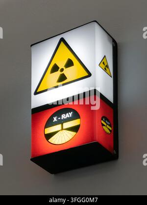 A wall-mounted LED medical warning light displaying a yellow radiation symbol on top and a red X-ray active indicator at the bottom, commonly used out Stock Photo