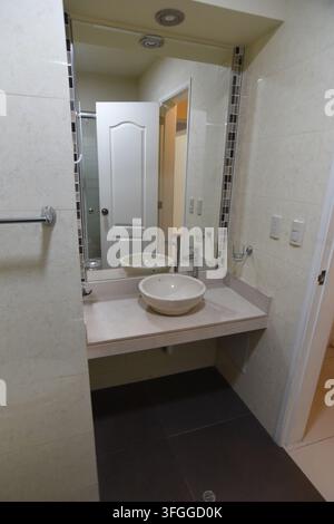 Modern Bathroom Vanity: A contemporary bathroom vanity features a vessel sink, sleek faucet, and large mirror reflecting the door Stock Photo