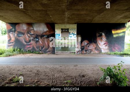 Large colorful portrait murals cover concrete supports beneath a road bridge in the Srodka area of Poznan. Stock Photo