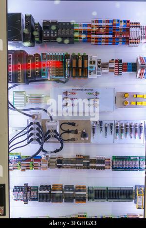 Inside an industrial electrical control panel featuring programmable logic controllers (PLC), Ethernet switches, terminal blocks, and complex wiring f Stock Photo
