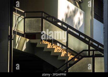 Low angle view of a modern architecture concrete staircase in Brazil, featuring dark metal handrails with textured glass panels beautifully illuminate Stock Photo