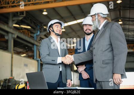Senior manager with manufacturing engineers shaking hands inside manufacturing plant. Concept of industrial business successful manufacturing deal, co Stock Photo