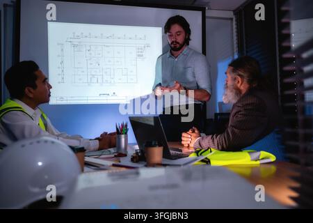 Engineering team discussing construction plan in dark meeting room with senior manager. Concept of brainstorming in construction project management wi Stock Photo