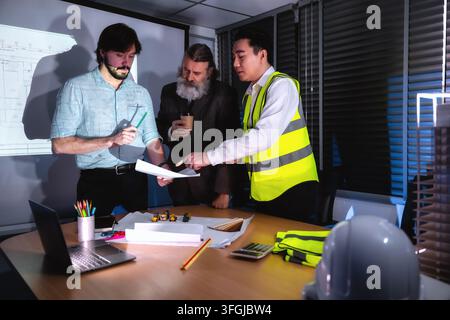 Construction management team discussing building layout drawing in boardroom with senior management. Concept of project planning, schedule of work, Br Stock Photo