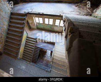 High angle view looking down an abandoned staircase inside the decaying historical sanatorium Heilstätte Grabowsee in Oranienburg, Brandenburg. Stock Photo