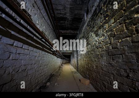 Abandoned dark brick tunnel corridor in former Heilstätte Grabowsee sanatorium near Berlin, Germany. Spooky lost place architecture. Stock Photo