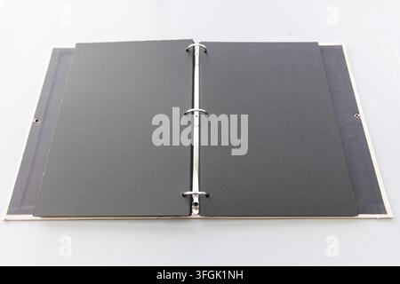 An open ring binder with black blank pages lies on white Stock Photo