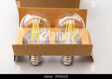 Two LED filament light bulbs are presented in brown cardboard packaging Stock Photo