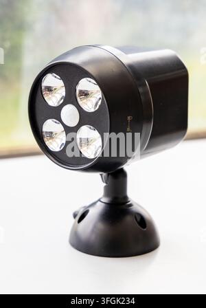 A black LED motion sensor spotlight stands on a white surface Stock Photo