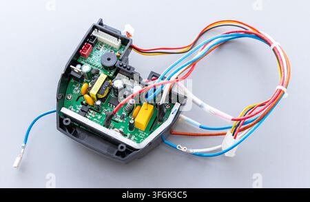 A green circuit board with colorful wires rests on a gray background Stock Photo