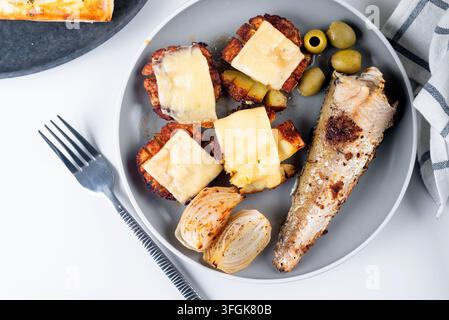 fried fish and a side dish of baked potato with cheese in plate for lunch on the table. Stock Photo