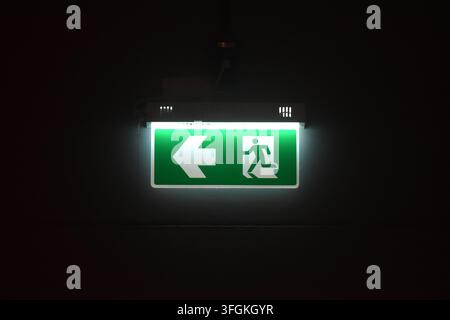 green electric light box sign fire exit door on wall in black background Stock Photo
