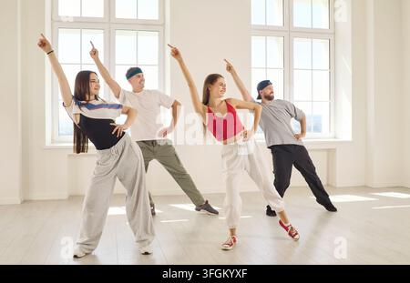 Four Friends Performing Energetic Group Dance Routine Together in Bright Studio Stock Photo