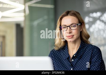 Professional woman working on laptop in office, focused business employee using computer for corporate tasks, digital communication and remote work productivity in modern workplace environment. Stock Photo