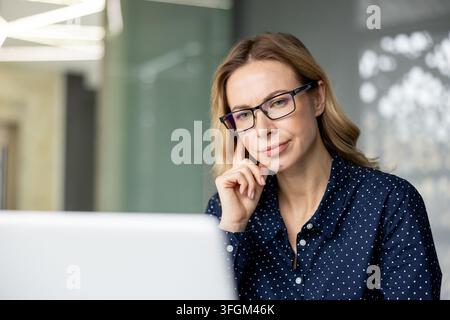 Professional woman working on laptop, focused business employee using computer in office, corporate career and digital communication, female entrepreneur with glasses thinking about project strategy. Stock Photo