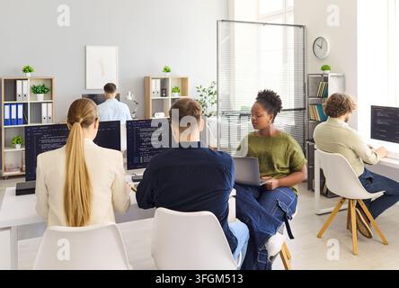 Developers collaborating in modern office, coding software on computers together Stock Photo