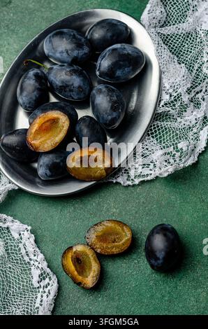 Fresh Ripe Plums with Green Basil Leaves on a Metal Plate Stock Photo