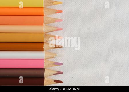 Row sharpened colored pencil tips lined up on left side white paper with ample copy space Stock Photo