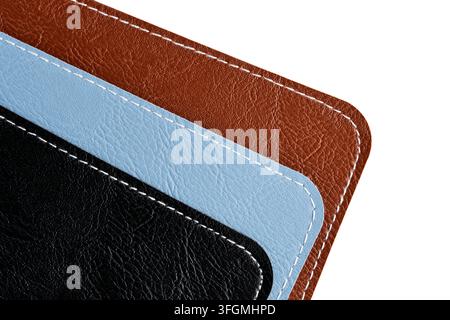 Close up shot stacked brown, blue, and black stitched leather accessories isolated on white Stock Photo