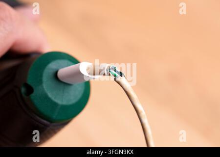 Damaged charging cable plugged into green cordless screwdriver close up Stock Photo