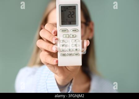 Energy efficiency and climate control, woman holding air conditioner remote with temperature setting for home comfort and sustainable living Stock Photo